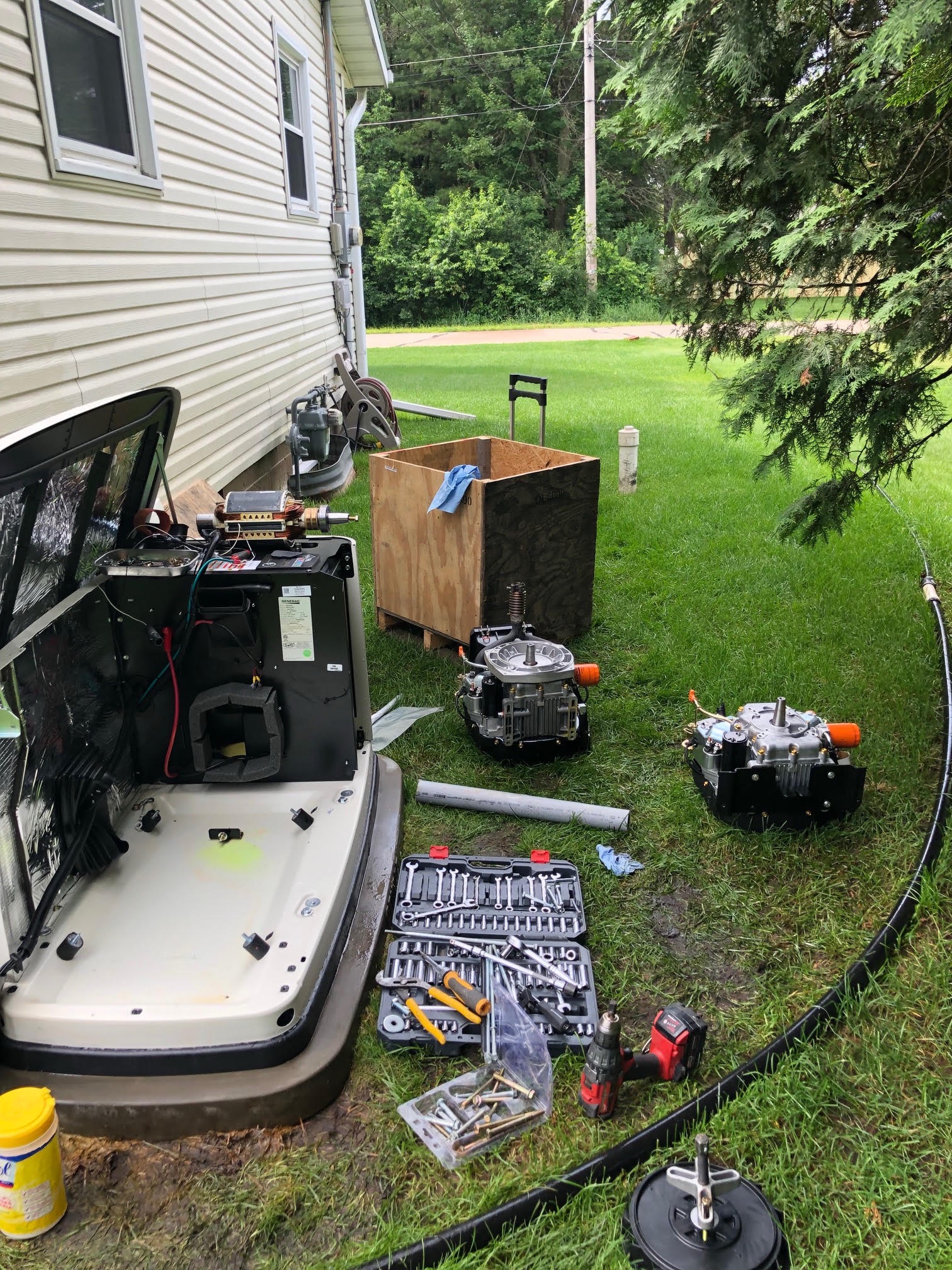 Generac generator disassembled for repair beside a home with tools and engine components on the grass