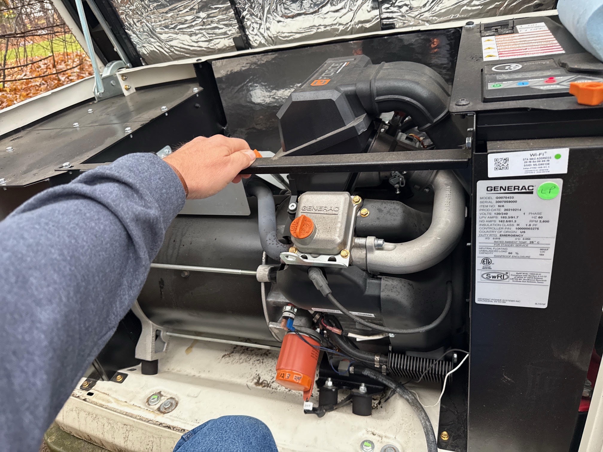 Technician servicing the engine of an open Generac standby generator