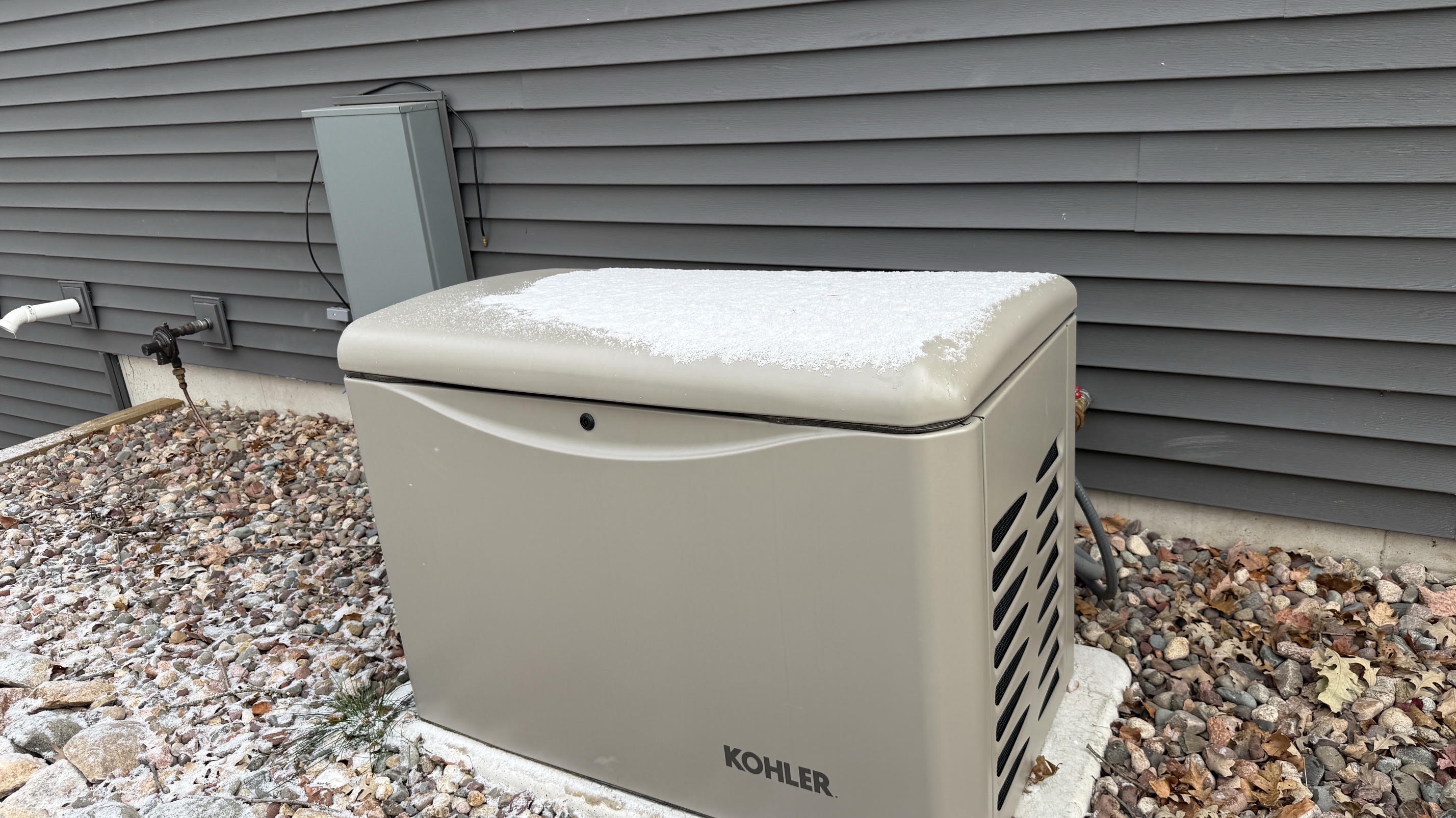 Kohler standby generator on a pad beside a home with fresh snow on top