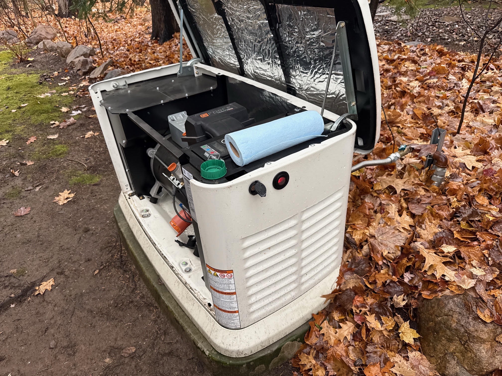 Standby generator opened for a fall maintenance service with oil and supplies on top