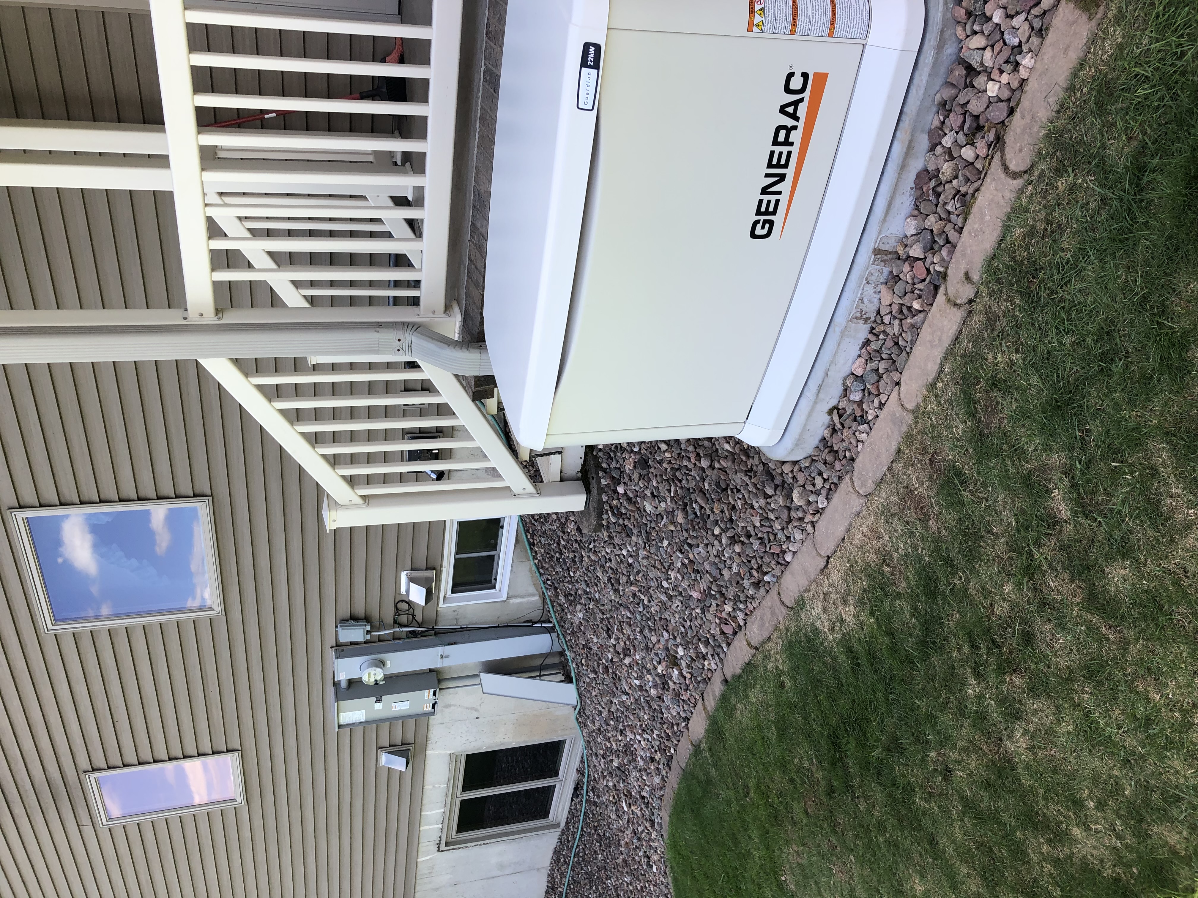 Generac Guardian standby generator installed beside a home's deck and landscaping