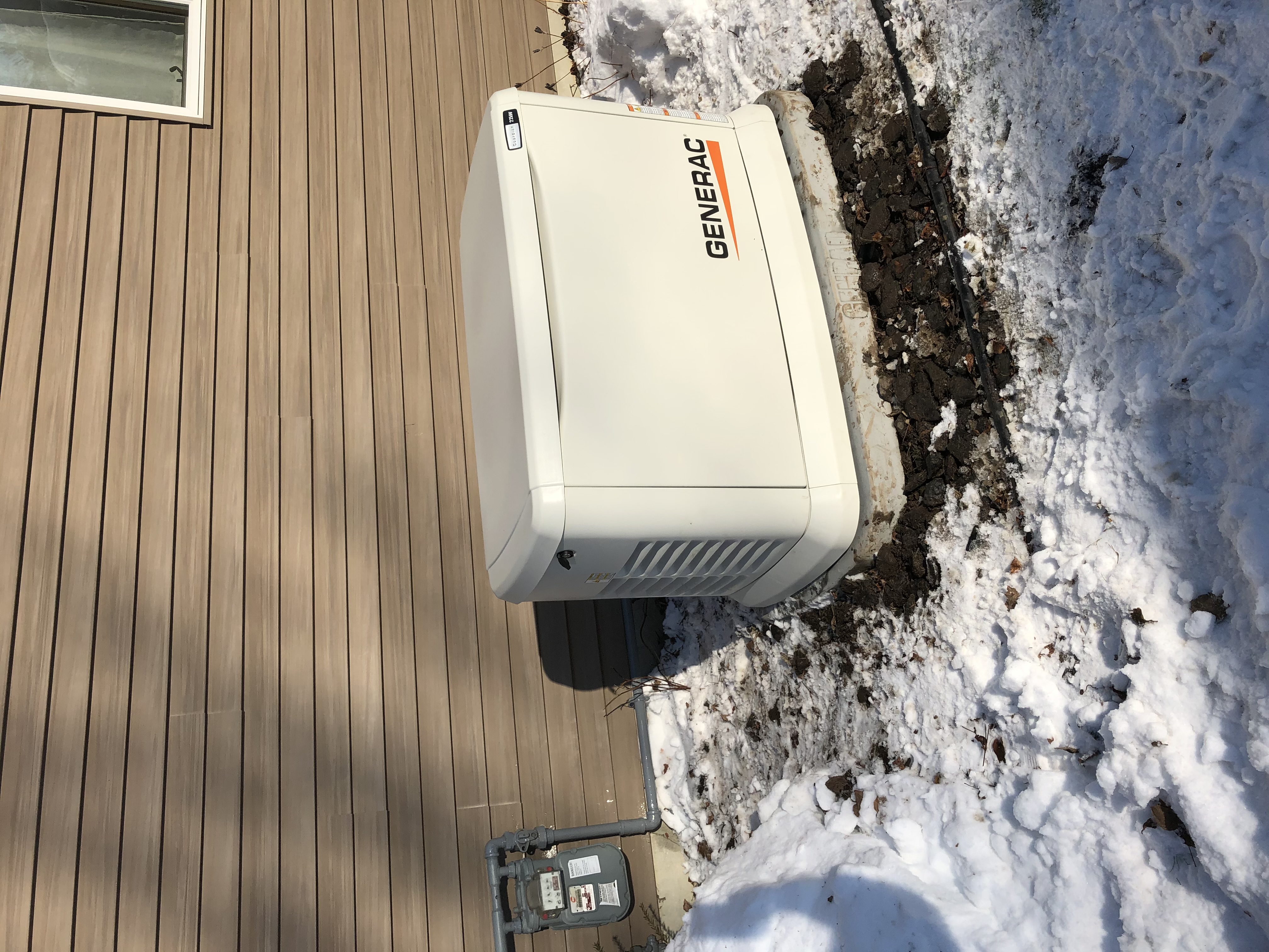 Generac Guardian standby generator beside a home in the snow